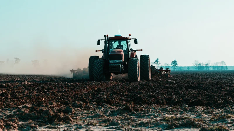 Large tractor pulling tillage equipment across a plowed field
