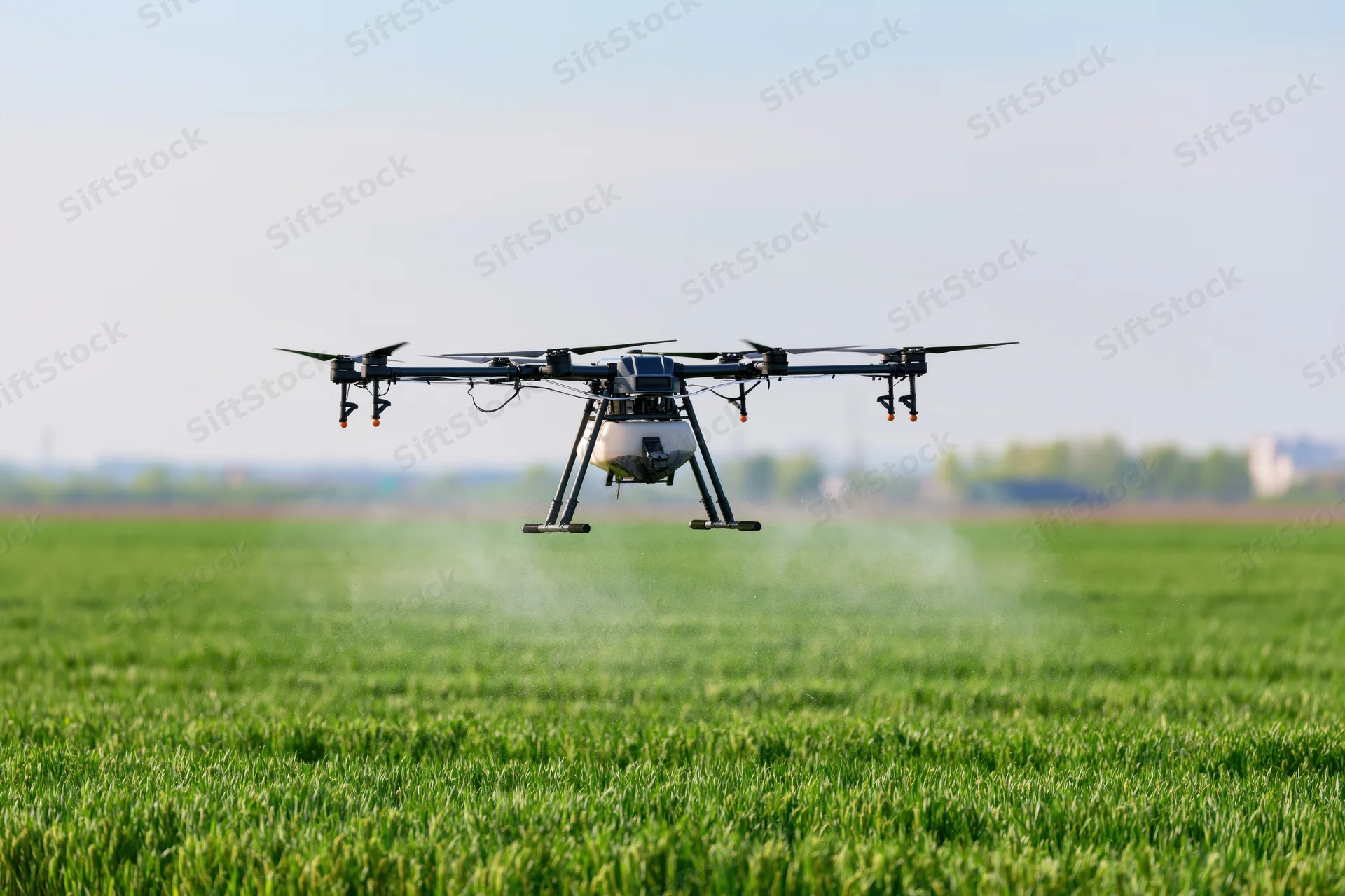 Agricultural drone hovering low over a green crop field spraying fertilizer
