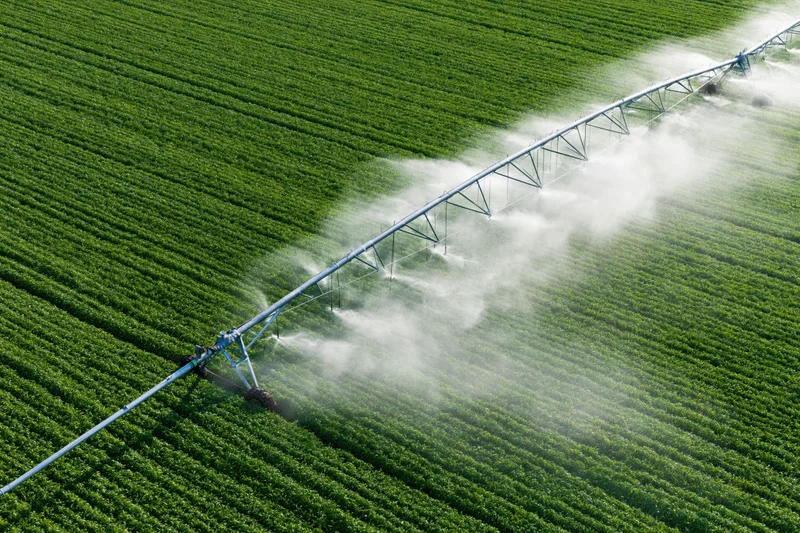 Aerial view of a center-pivot irrigation system spraying water over a green crop field