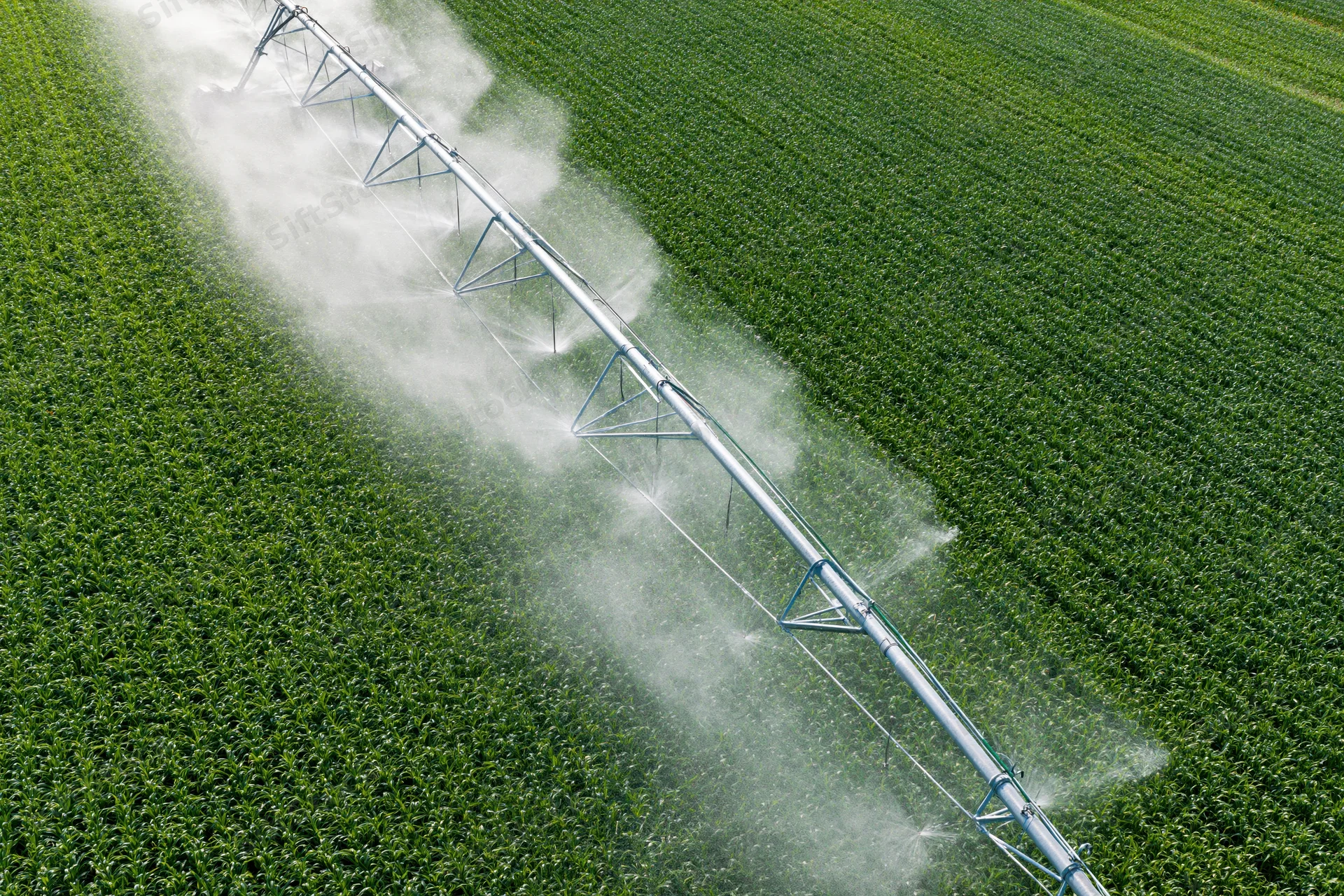Aerial view of a center-pivot irrigation system spraying water over a green crop field