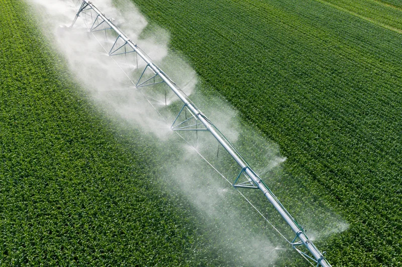 Aerial view of a center-pivot irrigation system spraying water over a green crop field