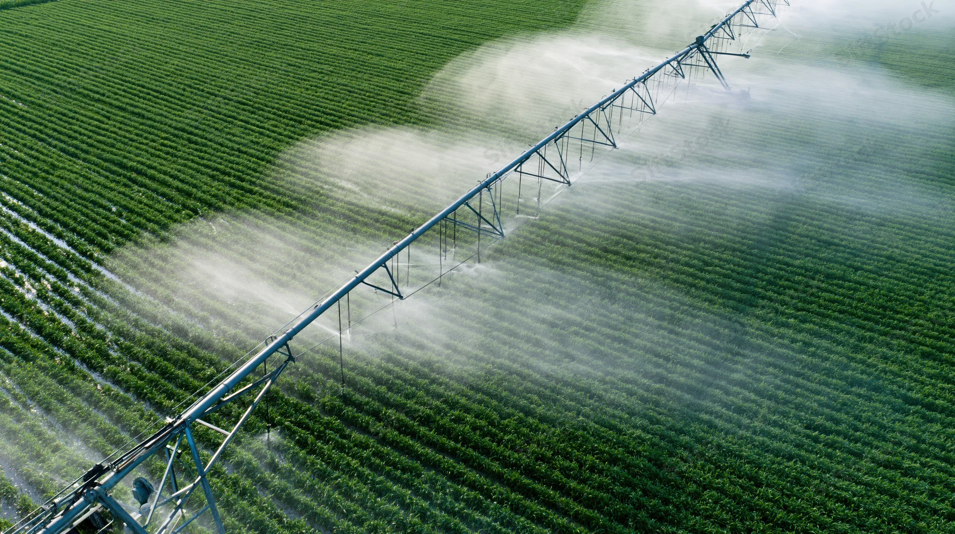 Aerial view of a center-pivot irrigation system spraying water over a green crop field