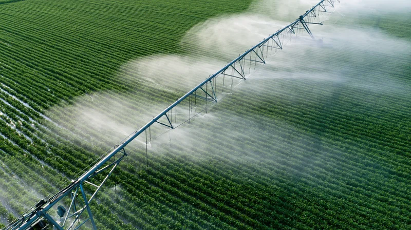 Aerial view of a center-pivot irrigation system spraying water over a green crop field