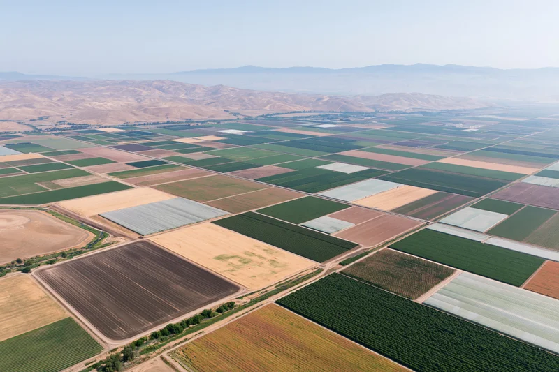 Aerial view of patchwork farmland in a valley with mountains in the distance