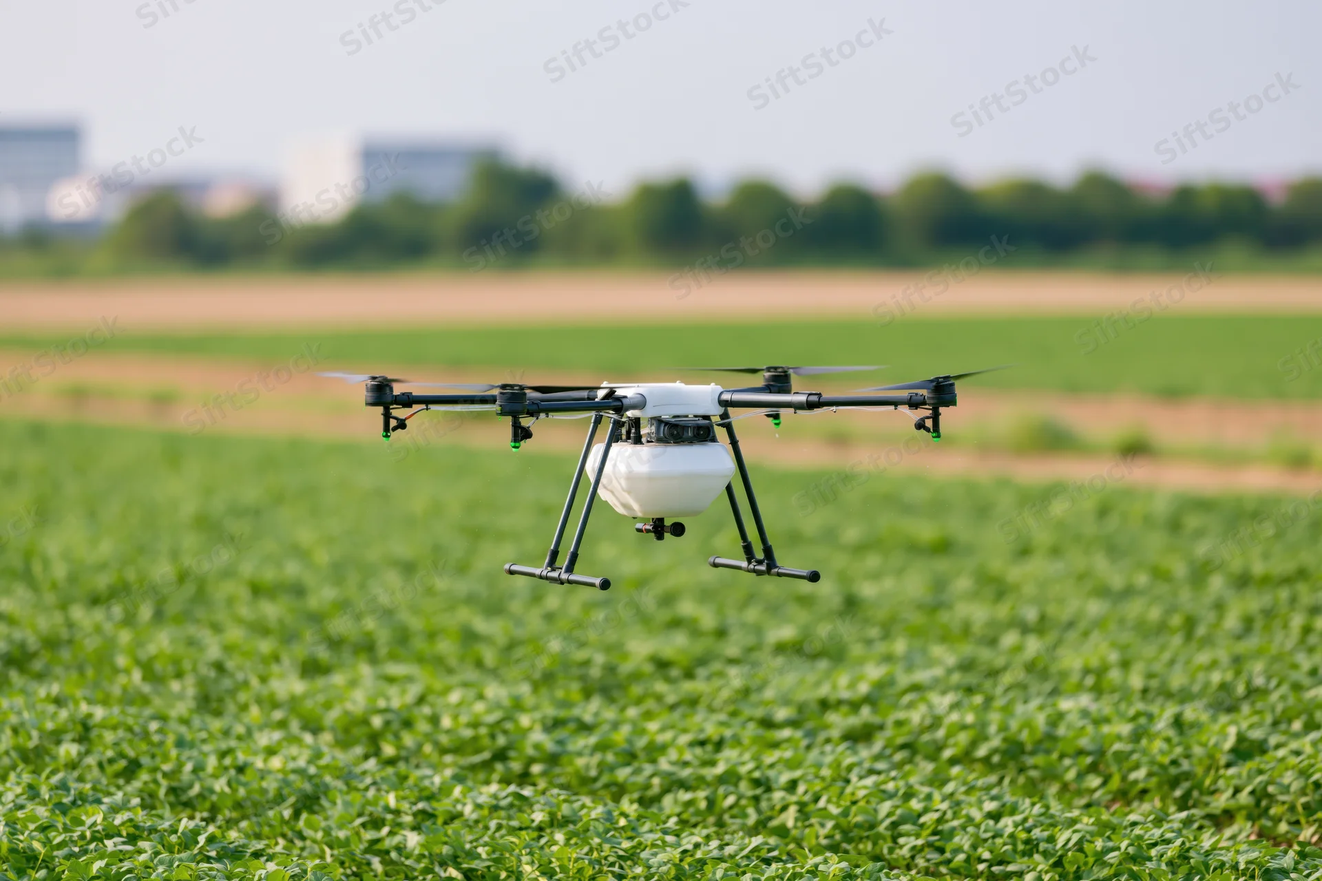 Agricultural sprayer drone hovering low over green crop field