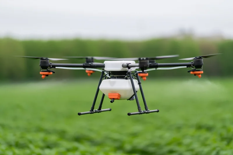 Agricultural sprayer drone hovering low over green crop field