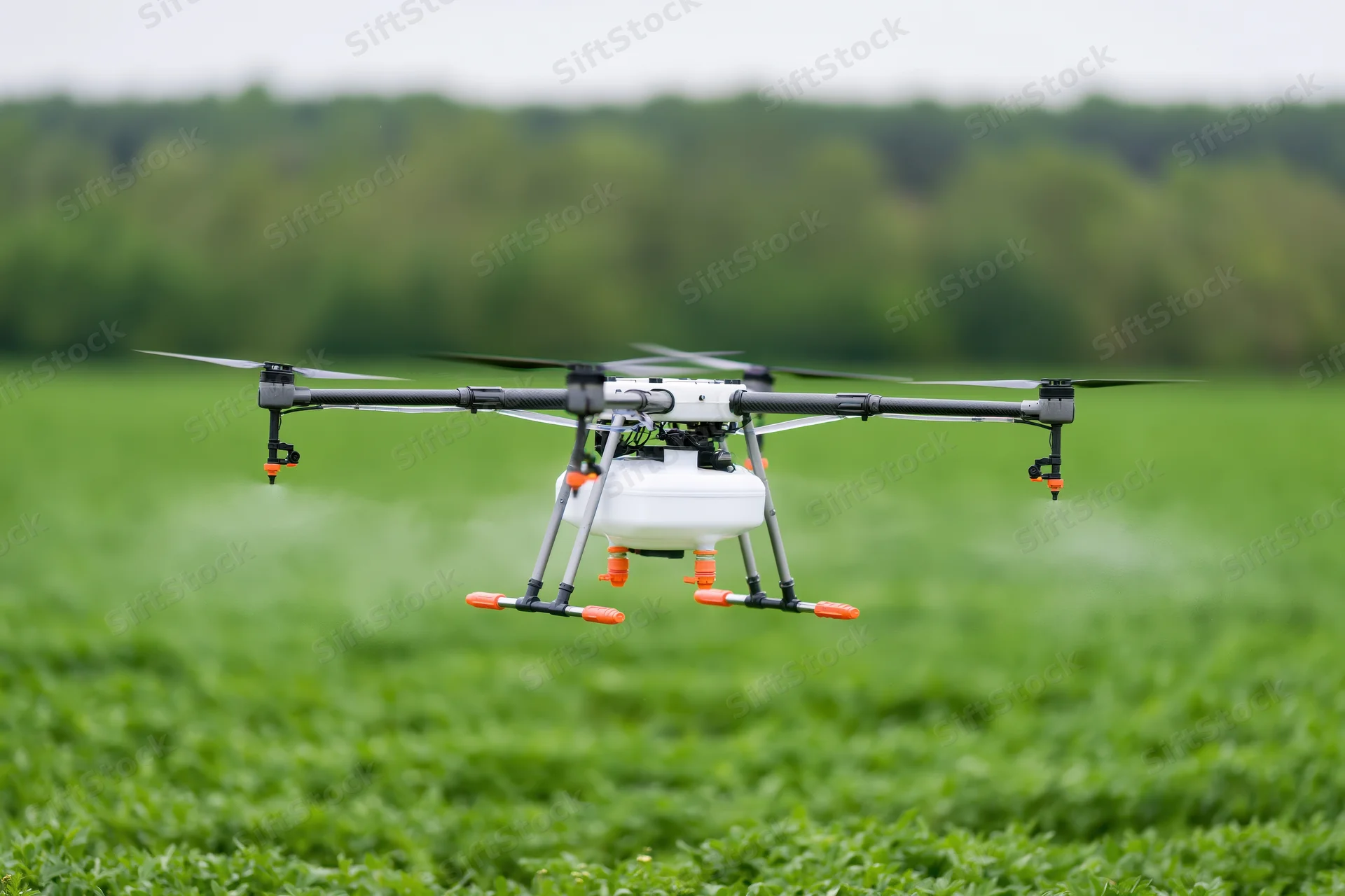 Agricultural sprayer drone hovering low over green crop field