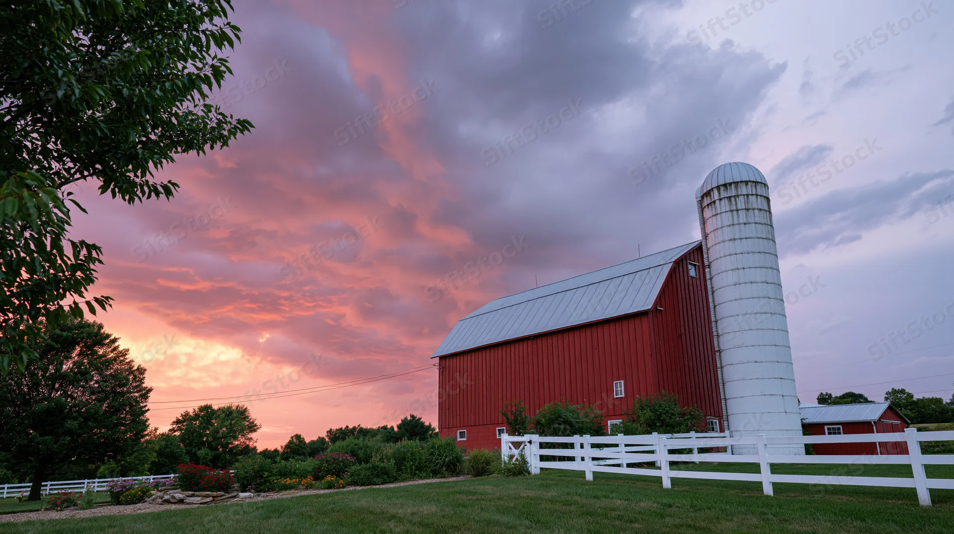 Red barn with white silo at sunset in rural countryside
