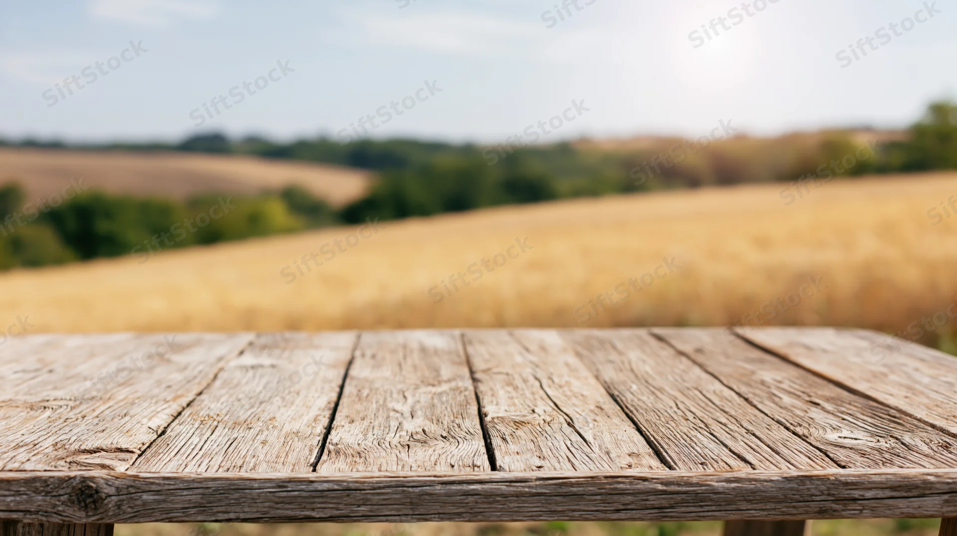 Weathered wooden table surface in a rural field under bright sky