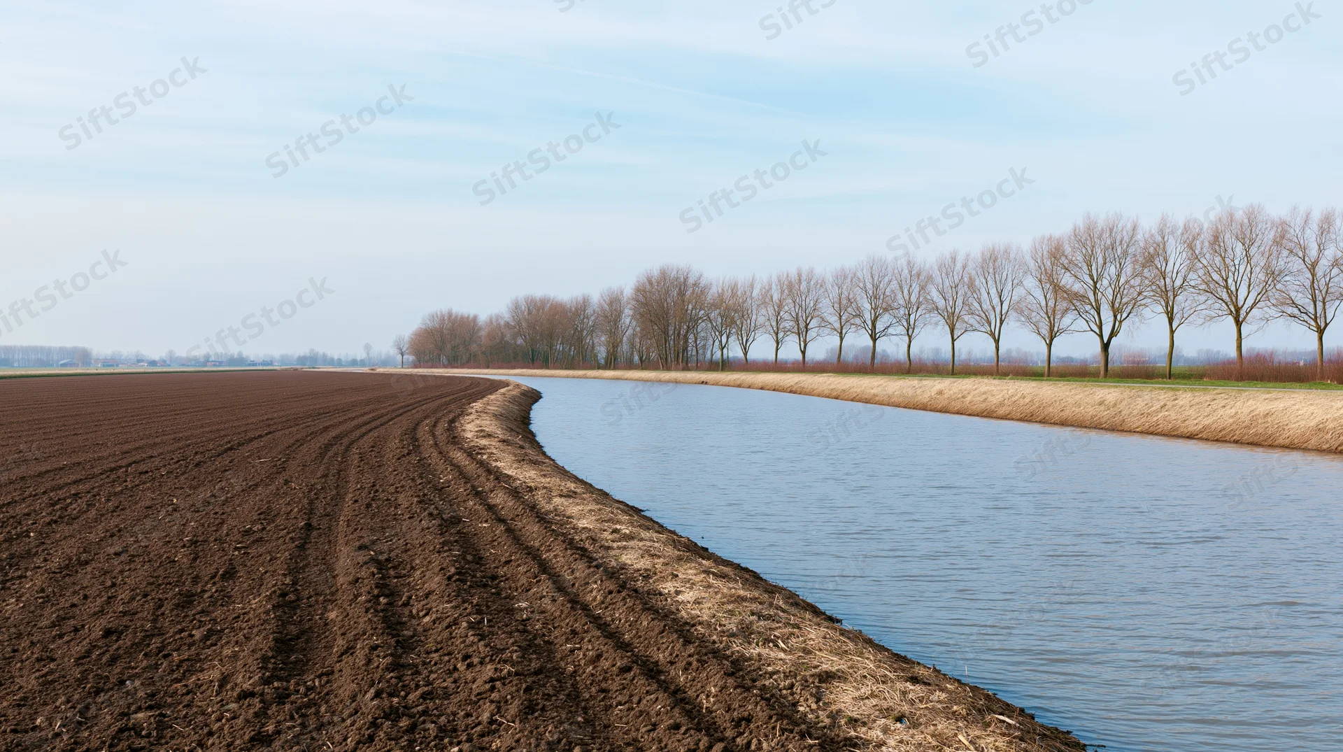 Ploughed field alongside a canal in a flat dutch polder landscape in early spring