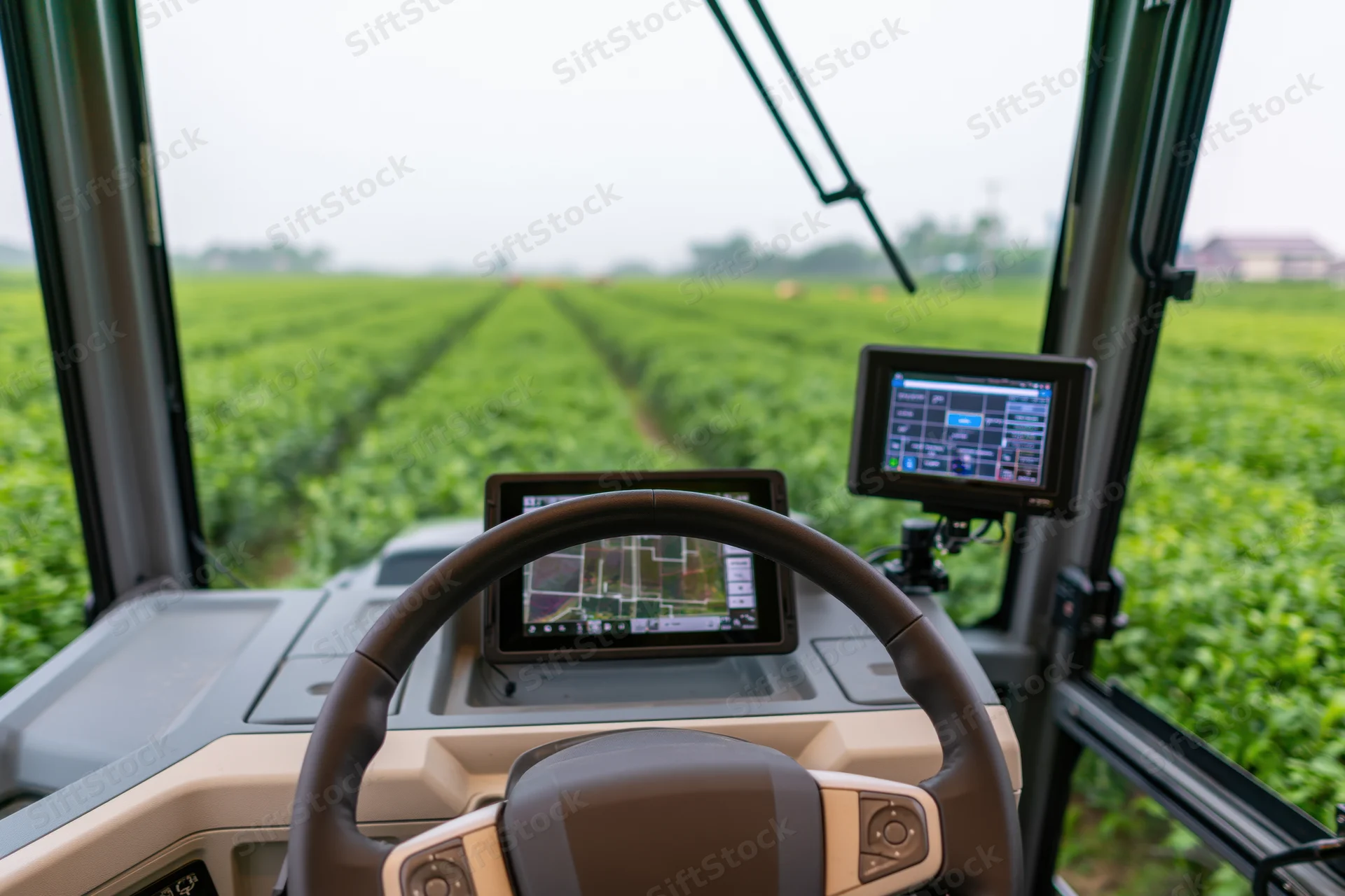 Interior of autonomous tractor cab showing steering wheel and digital displays overlooking a green crop field