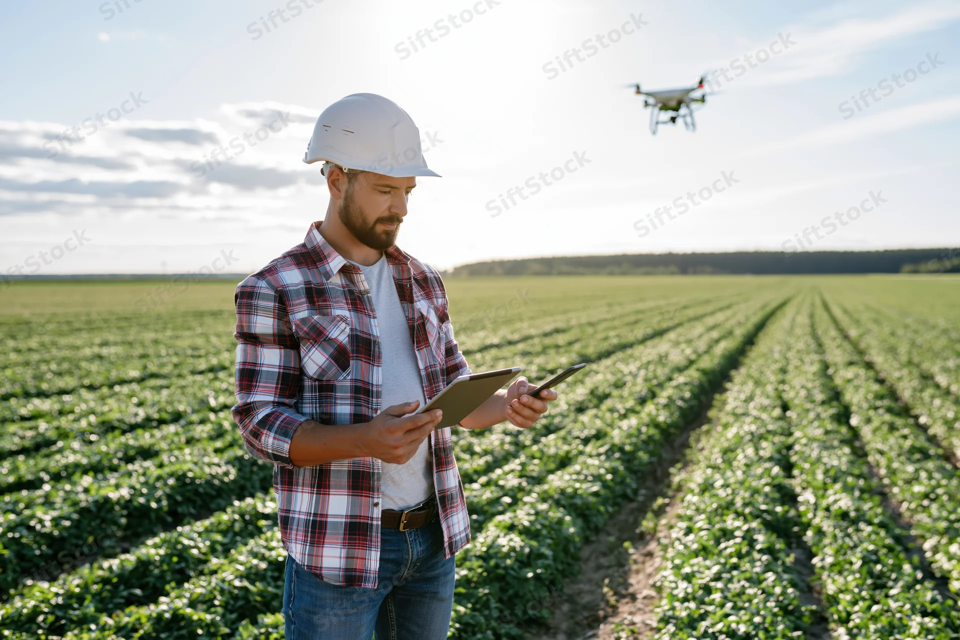 Farmer using tablet to control drone over crop field