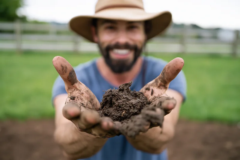 Man holding soil in his hands in a garden field