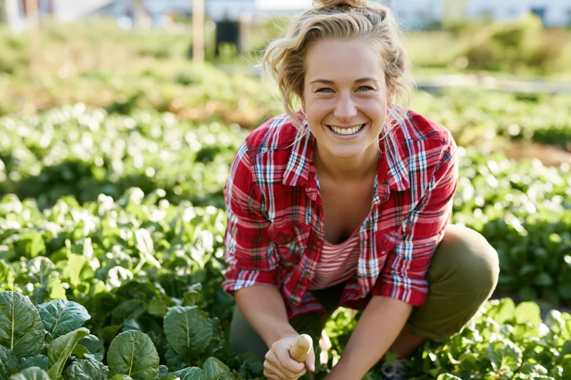 Young woman smiling while gardening in a vegetable field