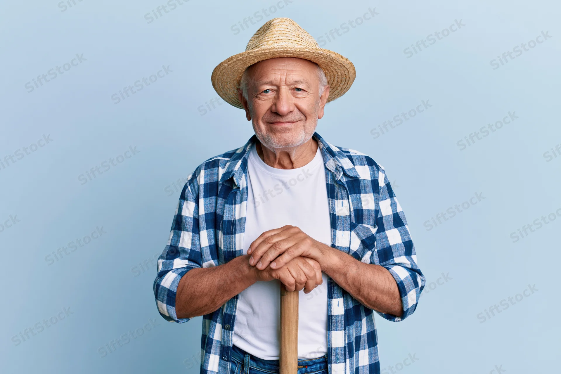 Senior man smiling while holding a wooden cane against a light blue background
