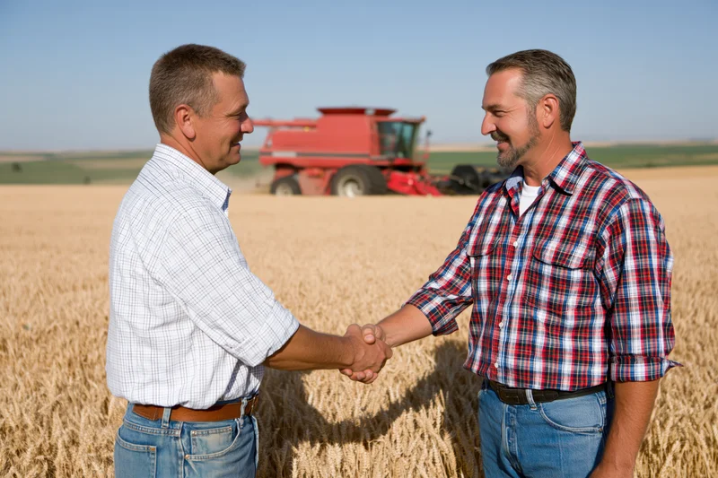 Two farmers shaking hands in a wheat field with a red tractor in the background