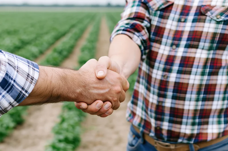 Two men shaking hands in a cultivated field