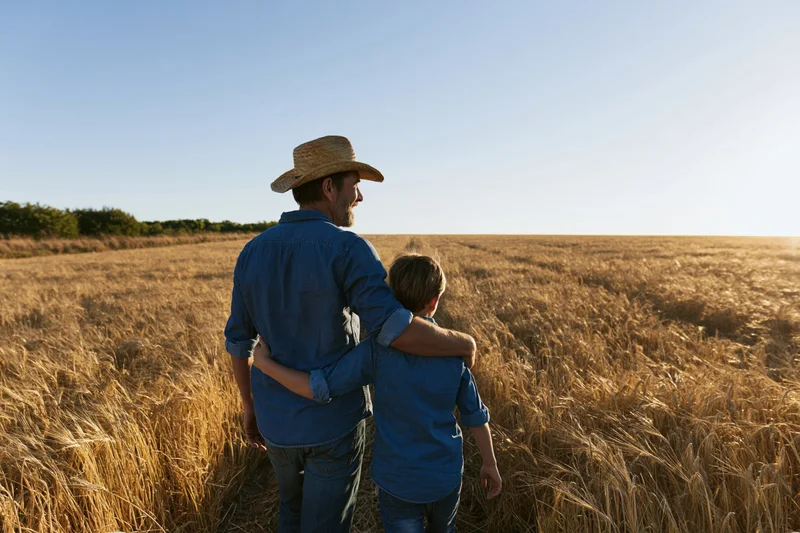 Father and son walking through a wheat field with arms around each other