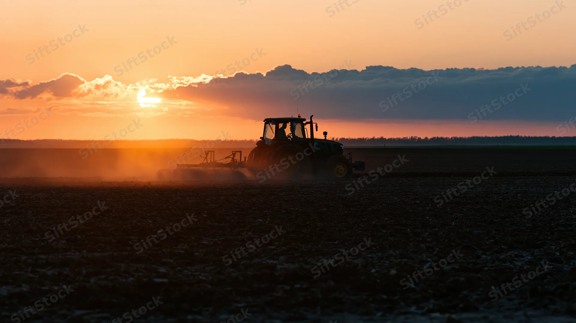 Tractor plowing a field at sunset