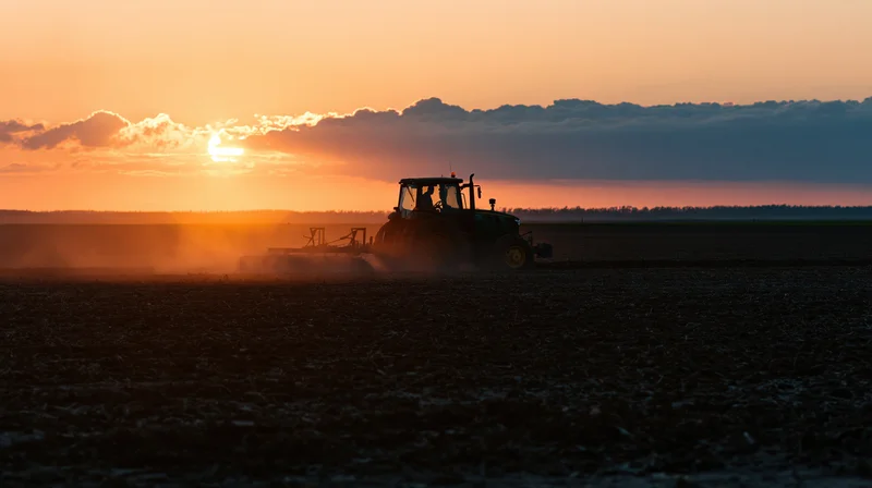 Tractor plowing a field at sunset