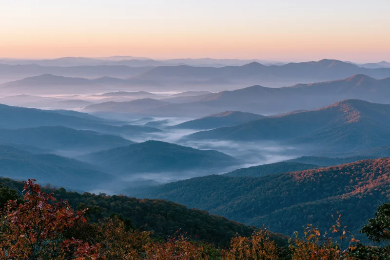 Layered appalachian mountain ridges receding into morning mist with autumn foliage in foreground