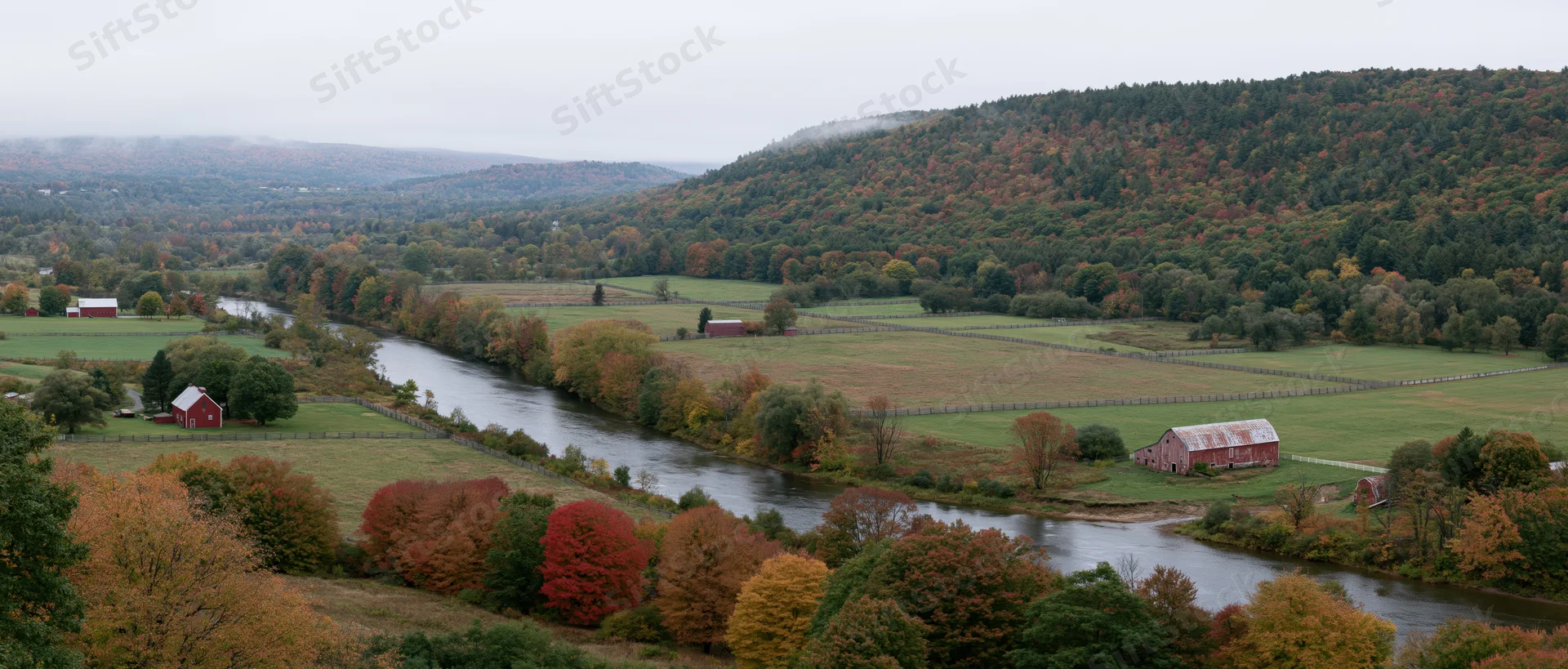 Winding river through autumn valley with red barns and colorful trees