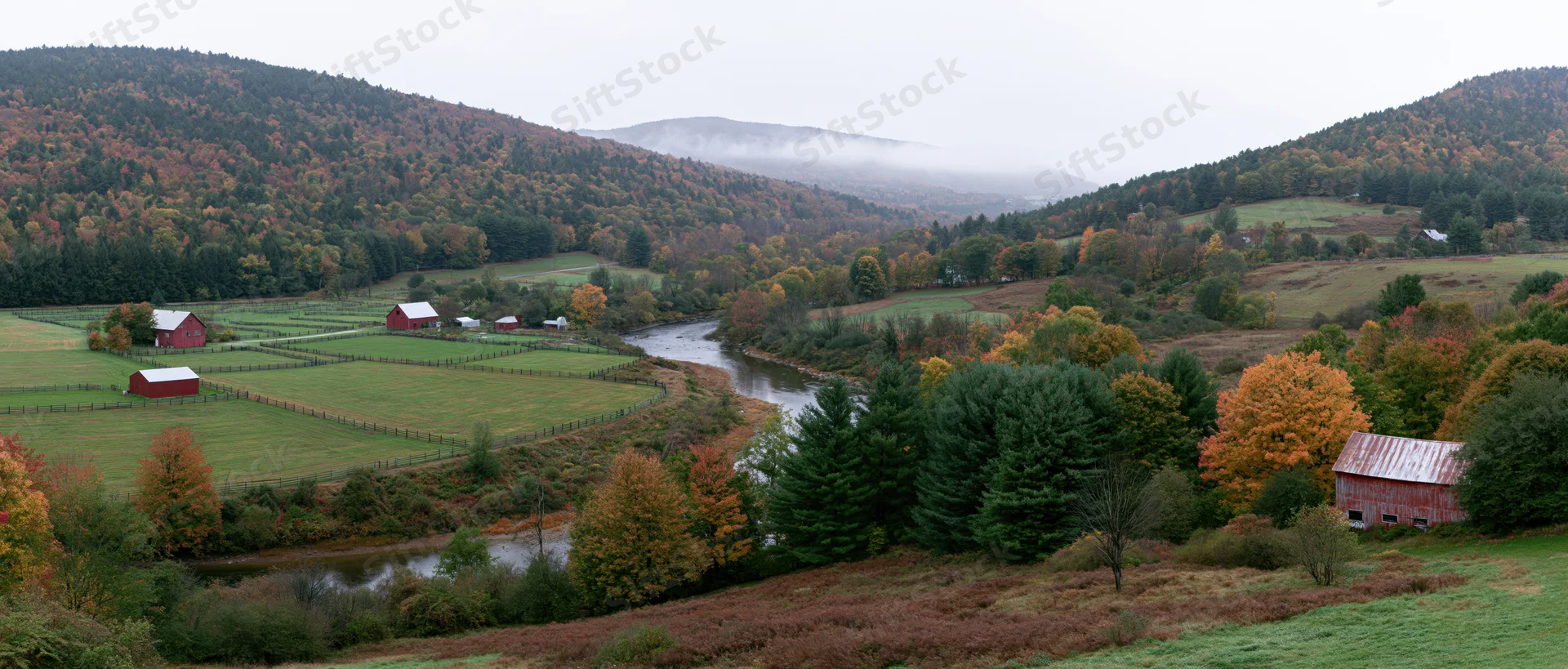 Winding river through autumn valley with red barns and colorful trees