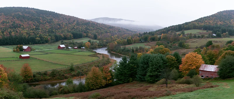 Winding river through autumn valley with red barns and colorful trees