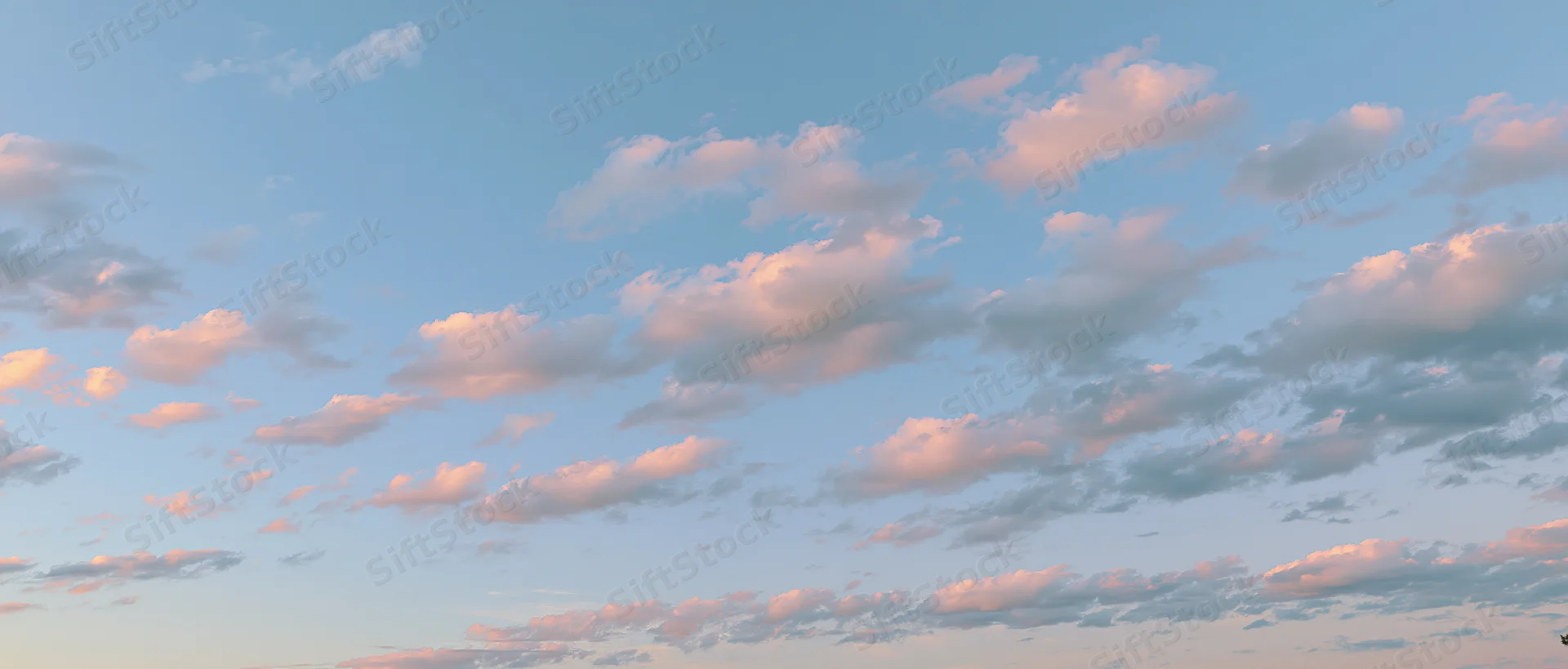 Soft cumulus clouds drifting across a clear sky at twilight