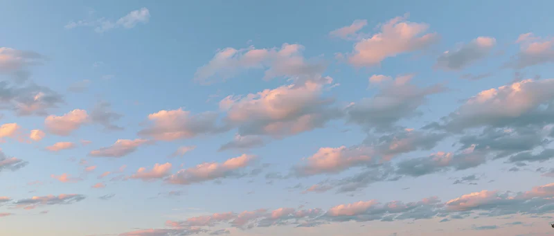 Soft cumulus clouds drifting across a clear sky at twilight