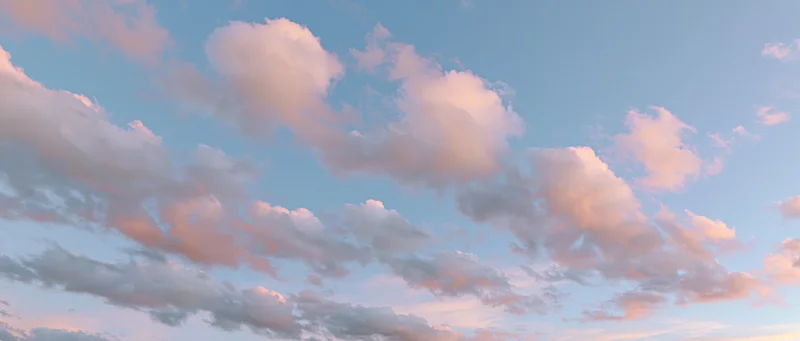 Soft cumulus clouds drifting across a blue sky at twilight