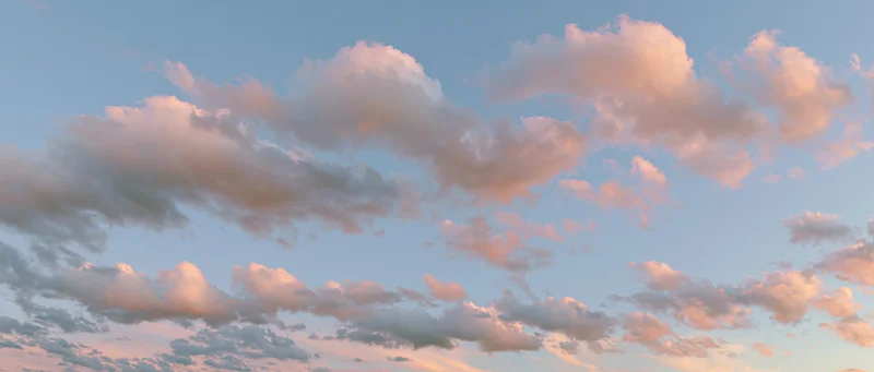 Soft cumulus clouds drifting across a clear sky at twilight