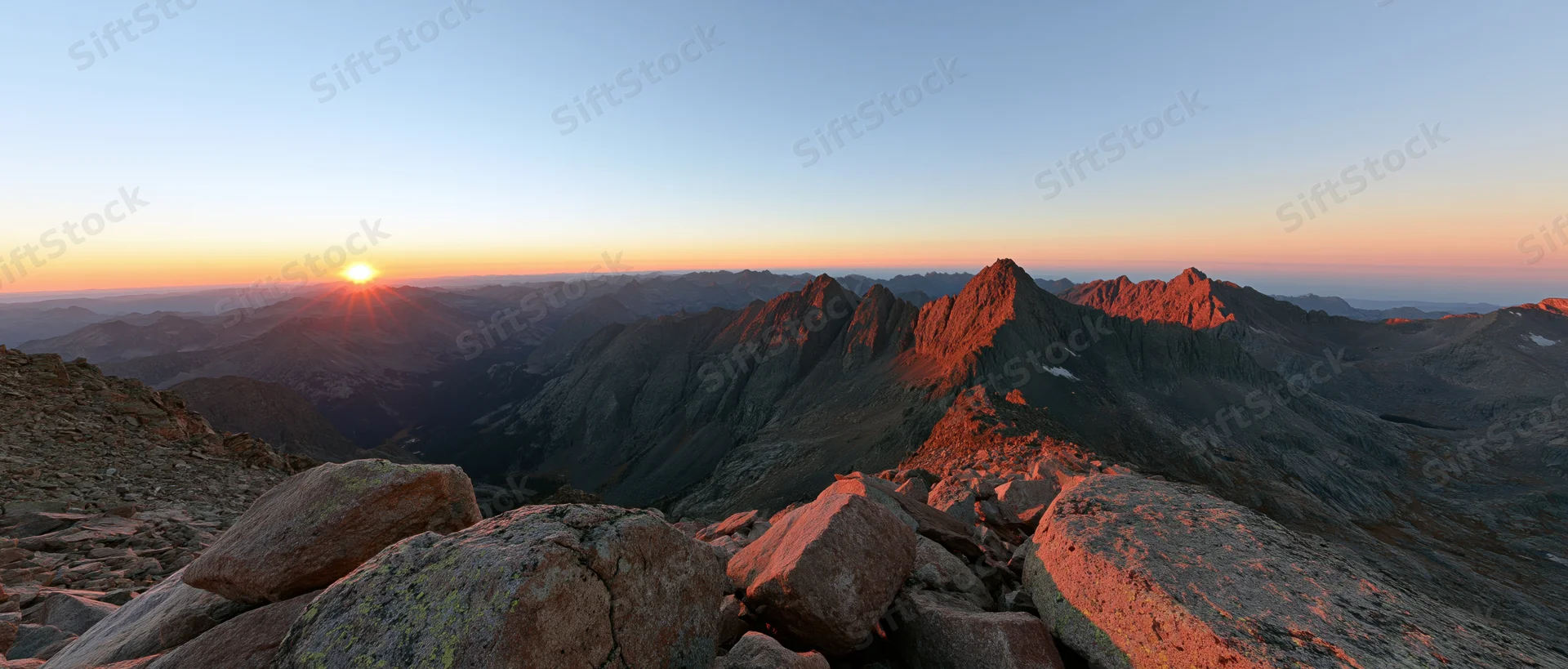 Panoramic view from rocky mountain ridge at sunrise over valley