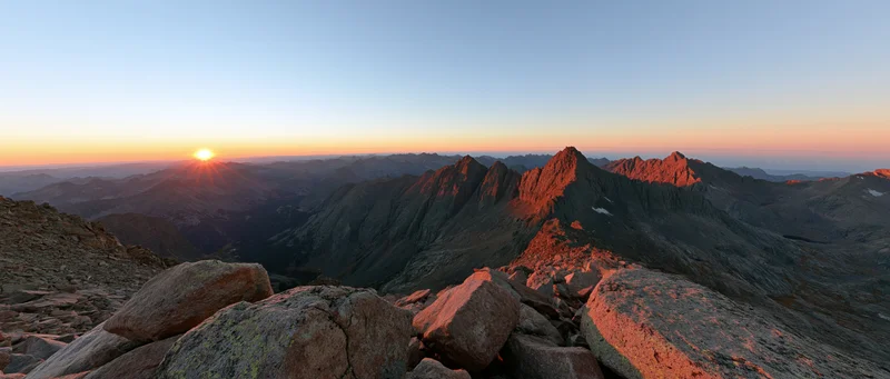Panoramic view from rocky mountain ridge at sunrise over valley
