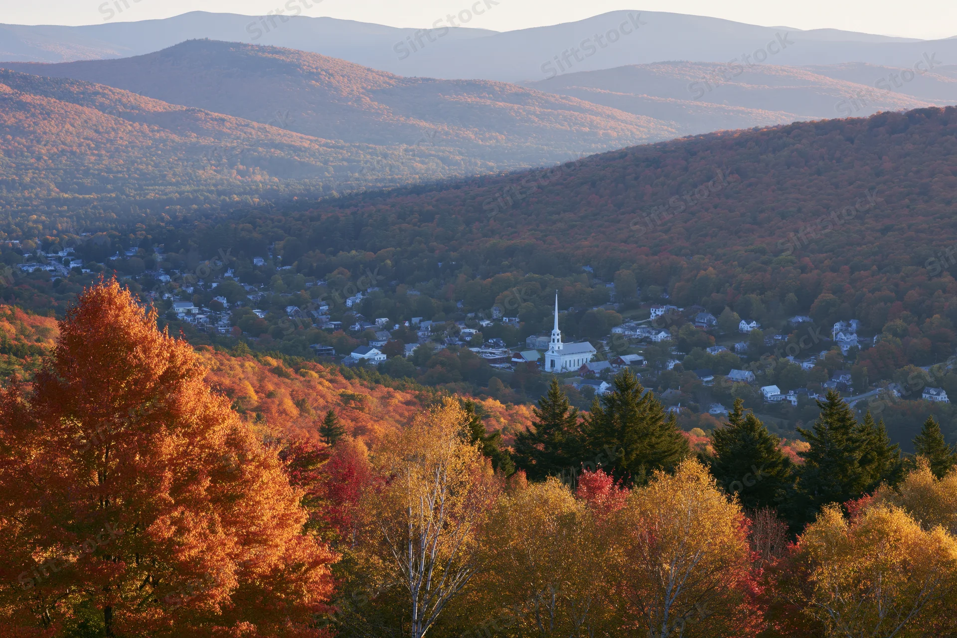Small new england village nestled in a valley surrounded by autumn foliage and mountains