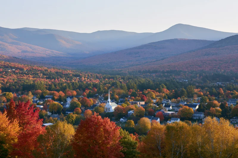 Small new england village nestled in a valley surrounded by autumn foliage and mountains
