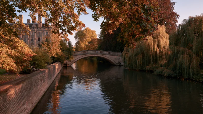 Stone arched bridge over calm river lined with autumn trees in cambridge