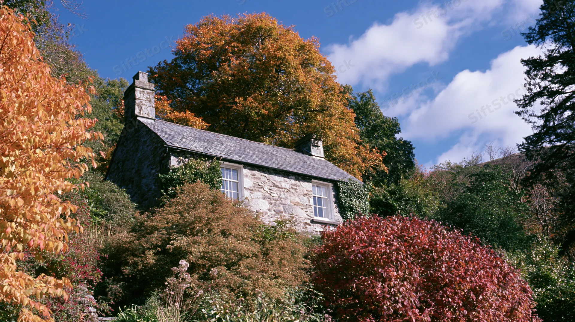 Stone cottage nestled among autumn foliage in a rural garden setting