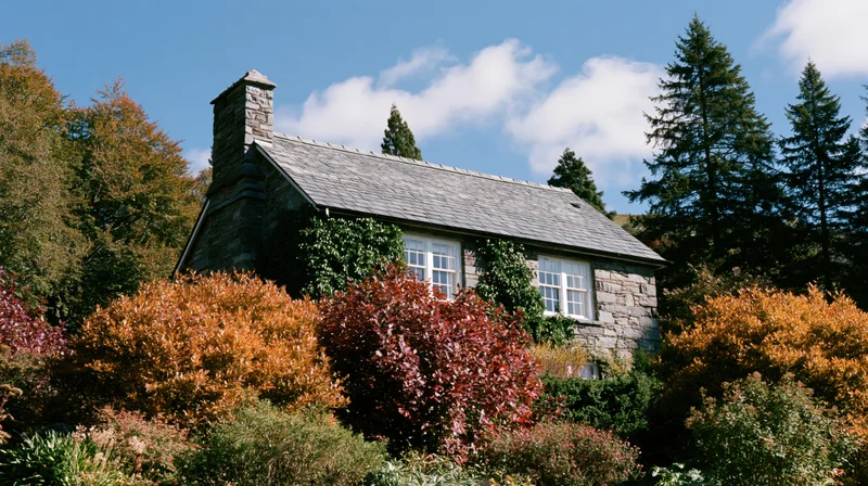 Stone cottage surrounded by autumn foliage in a rural garden setting