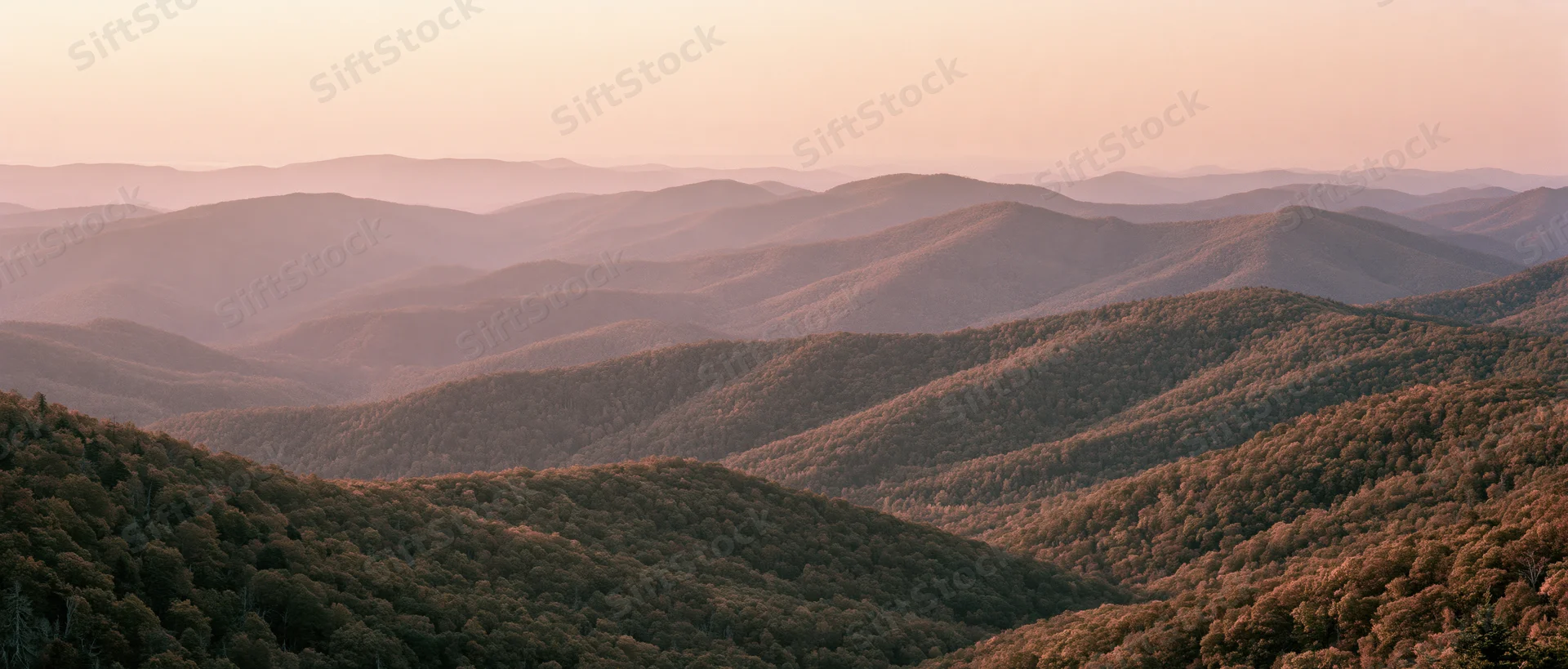 Panoramic view of rolling forested mountains at dusk