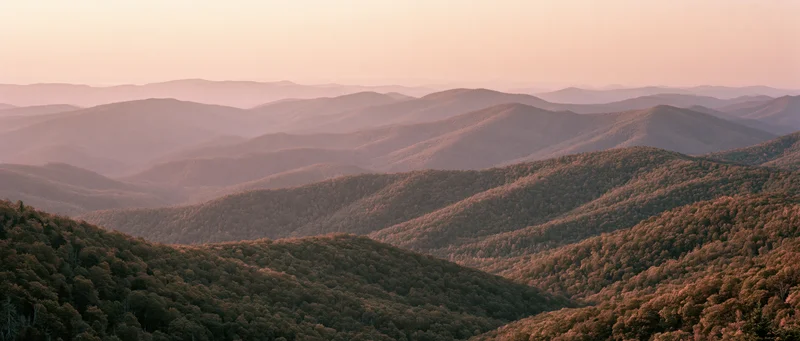 Panoramic view of rolling forested mountains at dusk