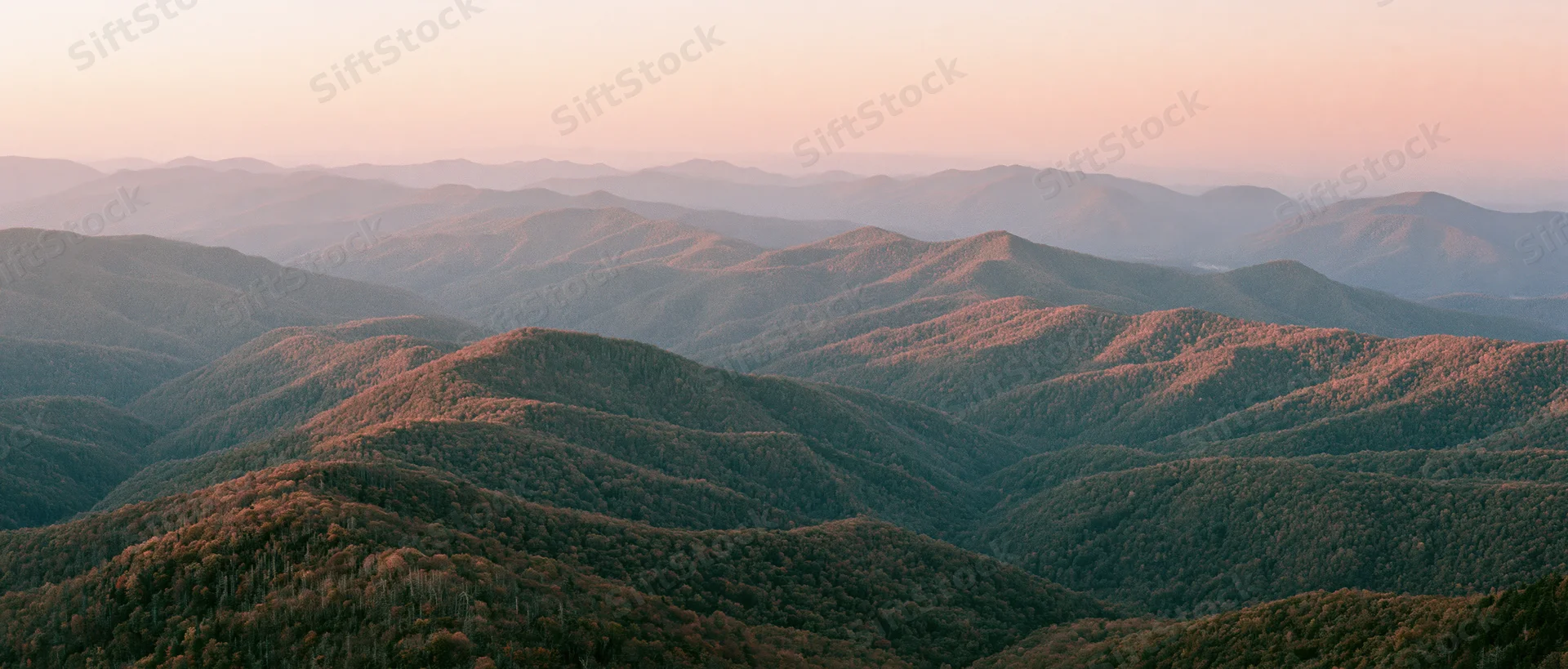 Panoramic view of rolling forested mountains at sunset