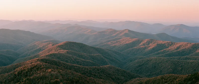 Panoramic view of rolling forested mountains at sunset