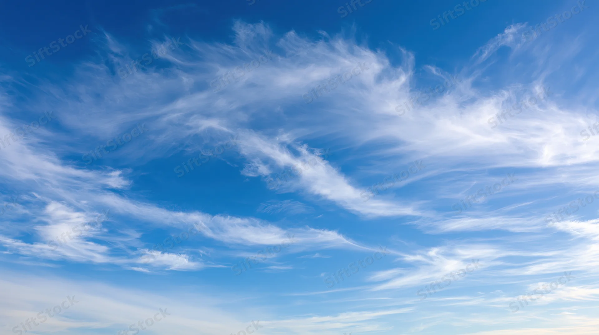 Wide panoramic view of open daytime sky filled with wispy cirrus clouds