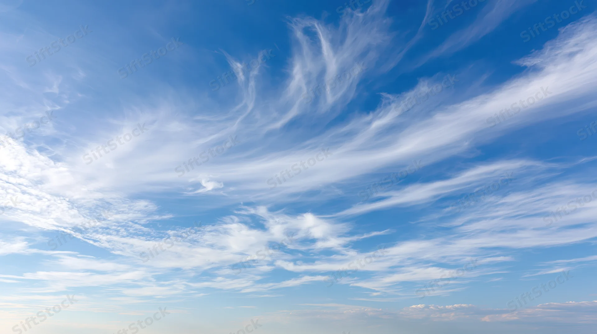 Wide panoramic view of open daytime sky filled with wispy cirrus clouds