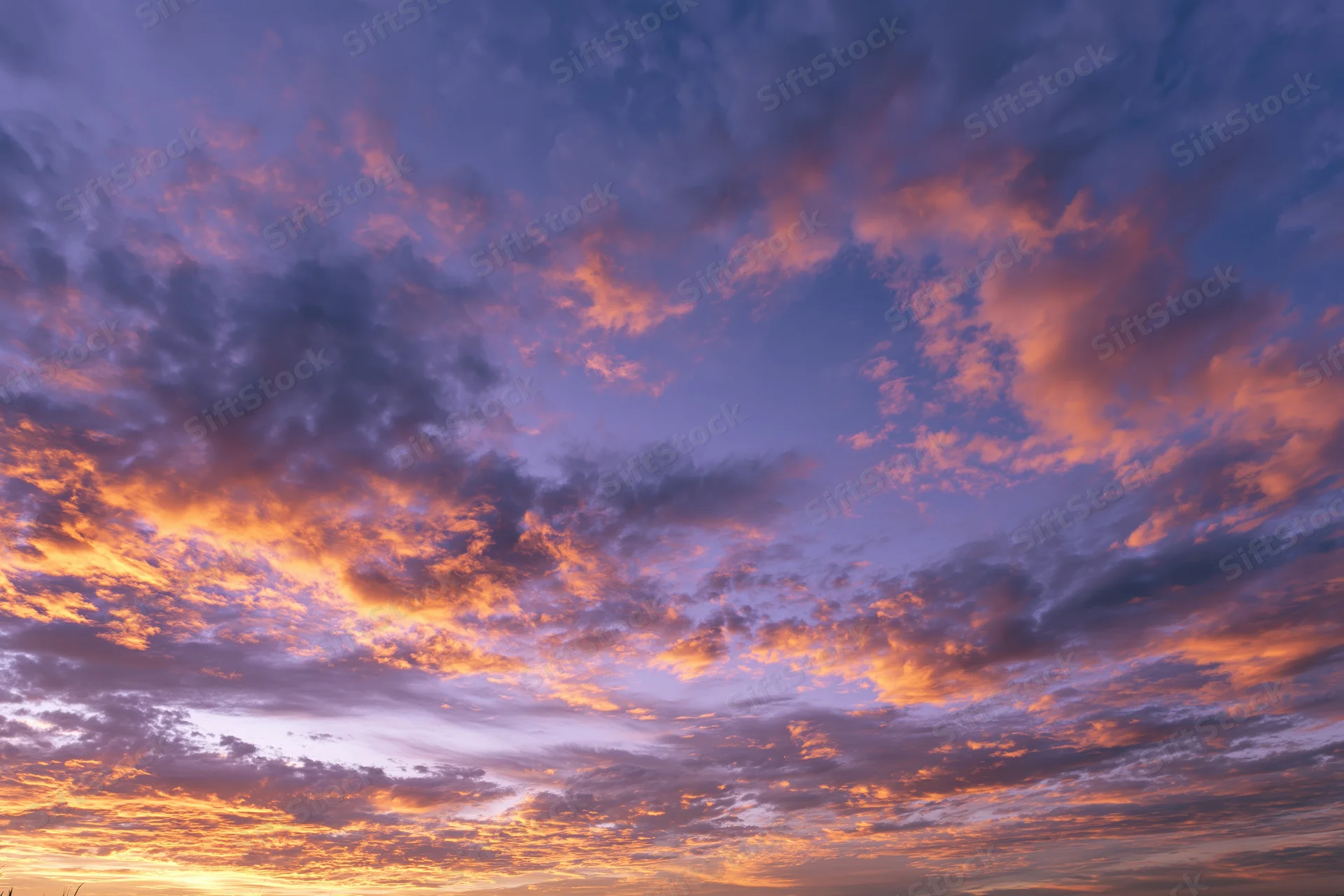 Dramatic sunset sky filled with orange and purple clouds, no horizon visible