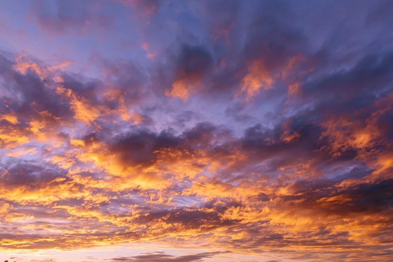 Dramatic sunset sky filled with orange and purple clouds, no horizon visible