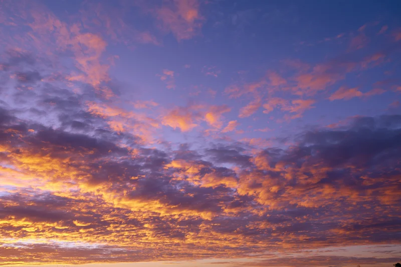 Dramatic sunset sky filled with orange and pink clouds against a deep blue twilight background