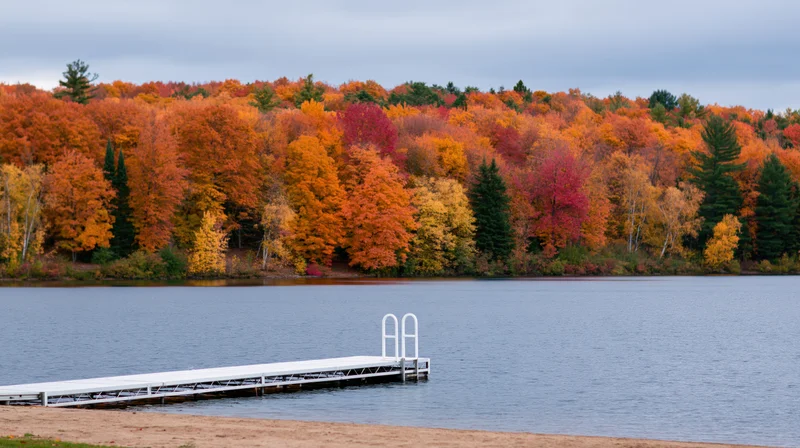 White metal dock extending into calm lake with autumn trees lining the shore