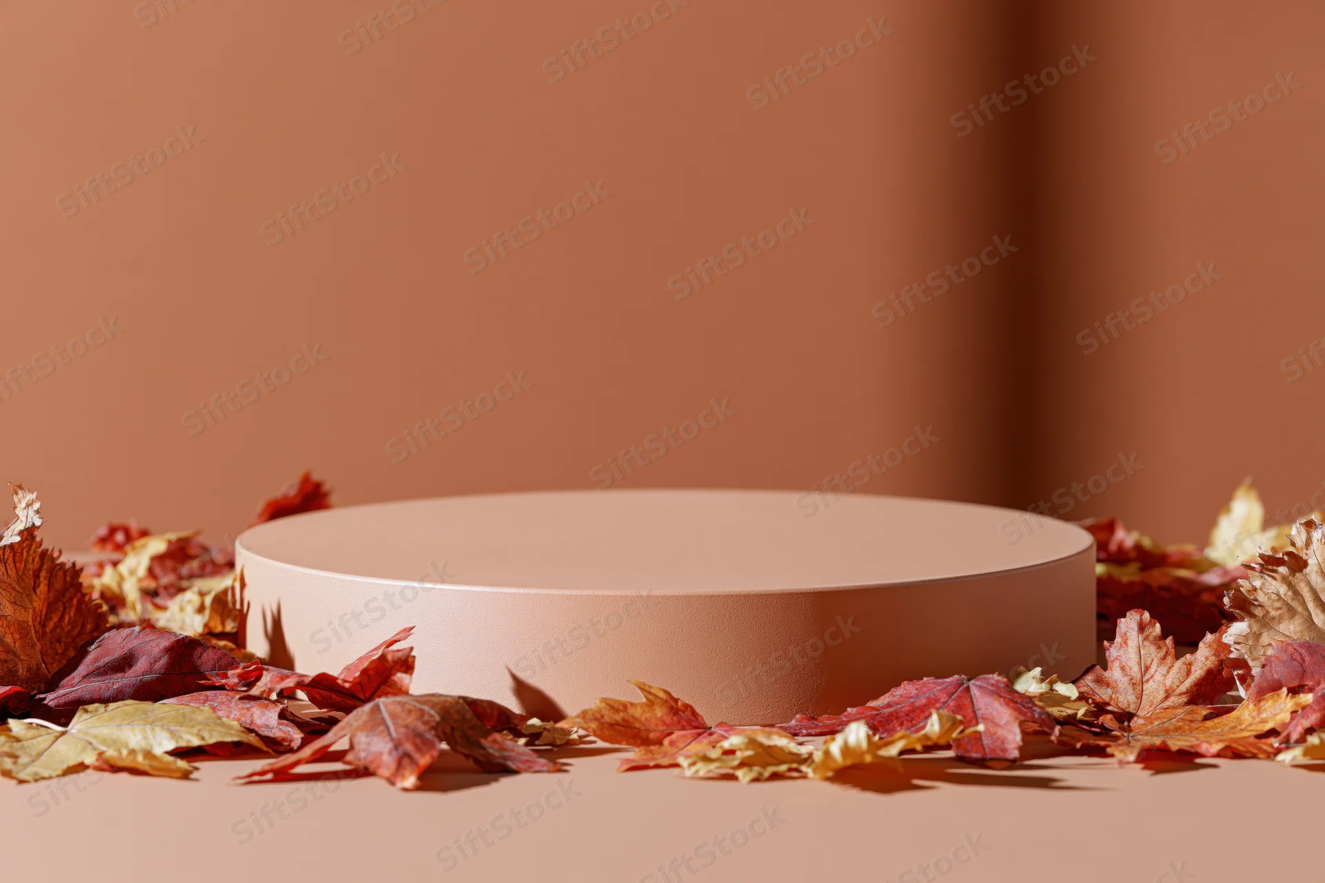 Round pedestal platform surrounded by autumn leaves on a warm-toned surface
